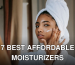 Young attentive ethnic female in bathrobe applying smear of moisturizing cream on face while looking in mirror at home