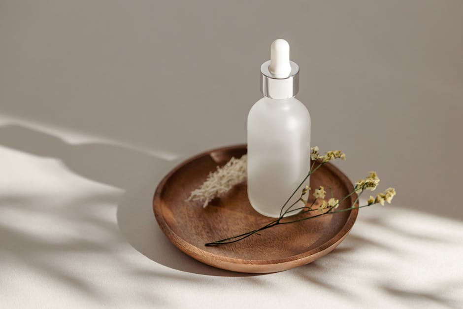 Elegant skincare bottle displayed on a wooden saucer with dried flowers and soft shadows.