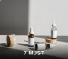 Minimalist composition of beauty bottles with droppers and containers on fabric under natural lighting.