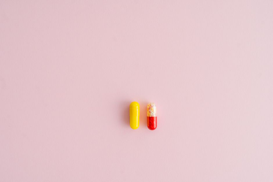Yellow and red capsules on a pink background, offering healthcare concepts.