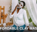 A woman enjoying a skincare routine with a clay face mask, seated indoors with a serene backdrop.