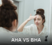 Young woman applying facial cream while looking at her reflection in the bathroom mirror.