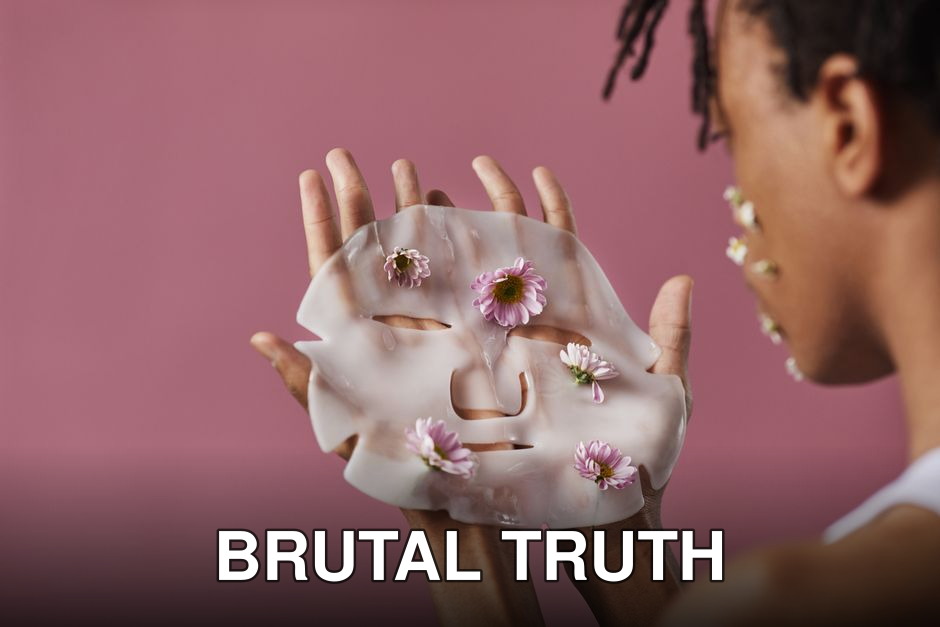 Close-up of hands holding a floral sheet mask with daisies against a pink background.