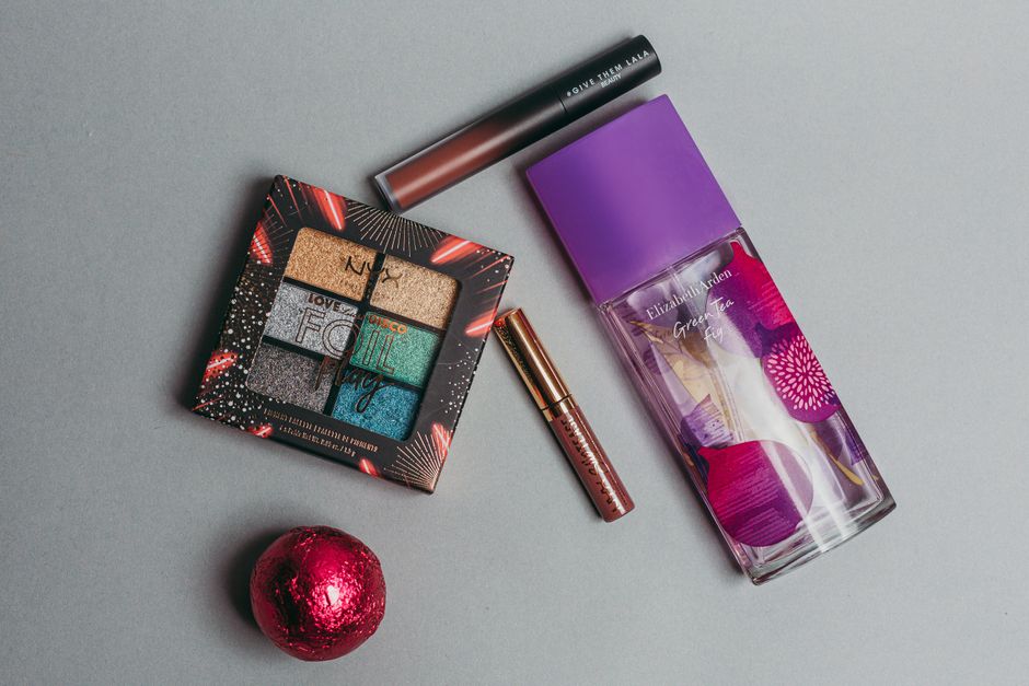 Stylish flat lay featuring a colorful palette, perfume, and lipstick on a neutral background.