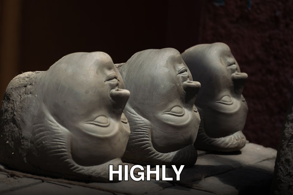 Three unfinished clay heads for Durga figures in a Kolkata workshop, bathed in sunlight.