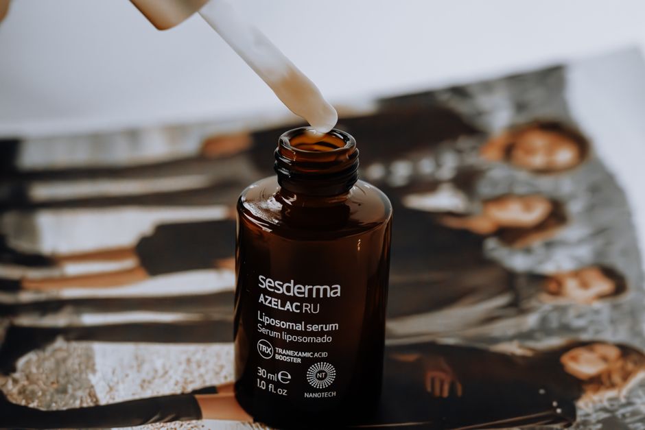 A liposomal serum bottle with a dropper placed on a magazine with blurred background.