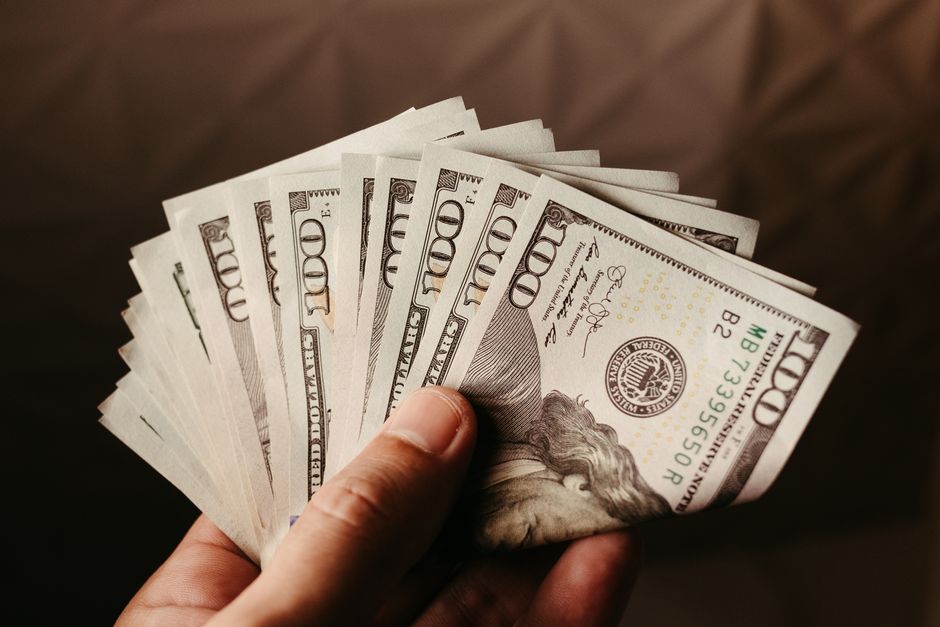 Fan of US hundred dollar bills held in hand, symbolizing wealth and finance.