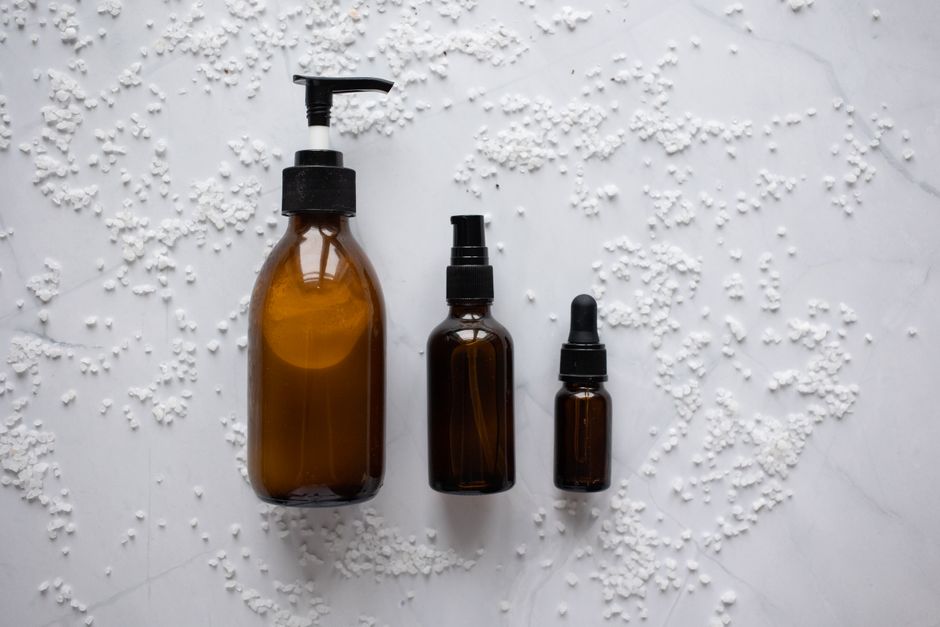 From above of various bottles with skincare cosmetic products placed on white marble table with salt