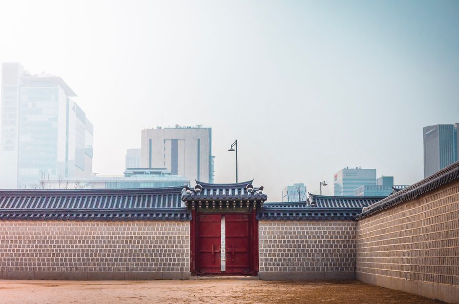 A historic Korean gate set against Seoul's modern skyline, showcasing cultural contrast.