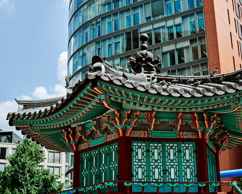 Colorful Korean pavilion contrasting with modern architecture in Berlin, Germany.