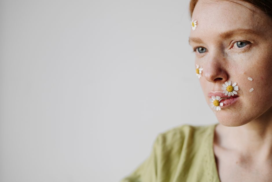 Woman's face adorned with daisies, conveying a natural and artistic expression.