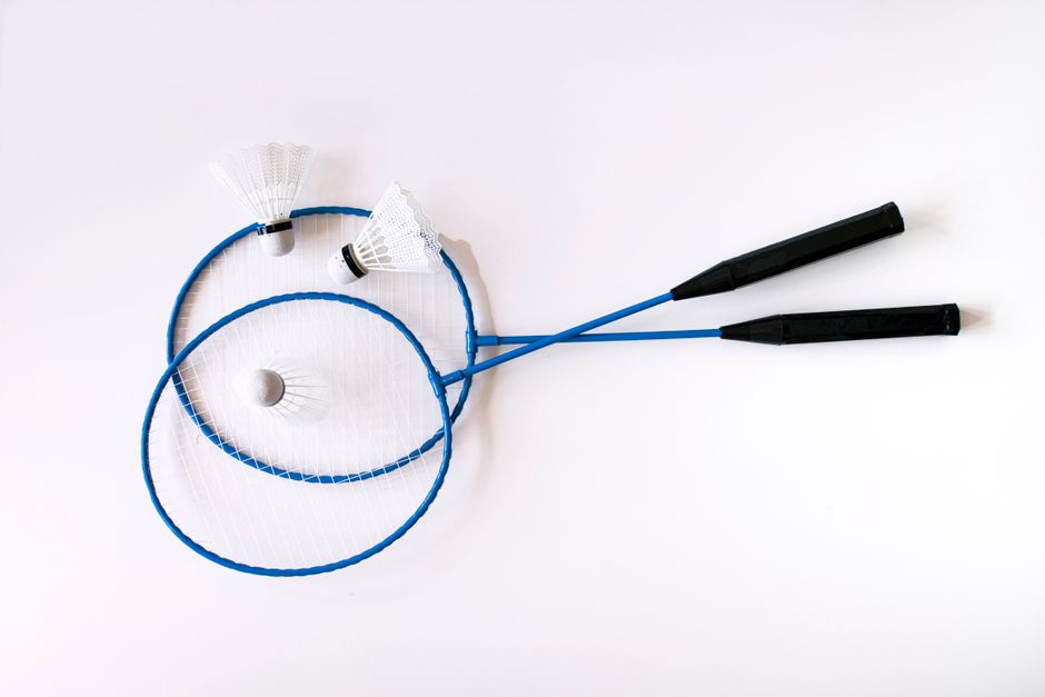 Top view of two blue badminton rackets and shuttlecocks on a white background, perfect for sports equipment showcases.