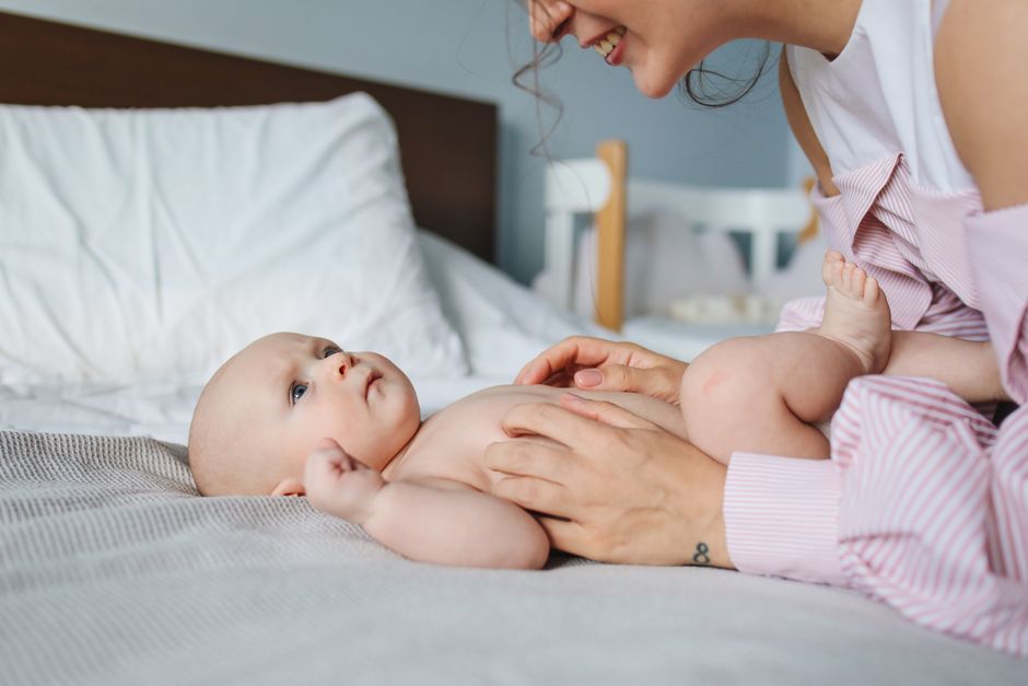 A tender moment between a mother and her baby lying on a bed, capturing love and bonding.