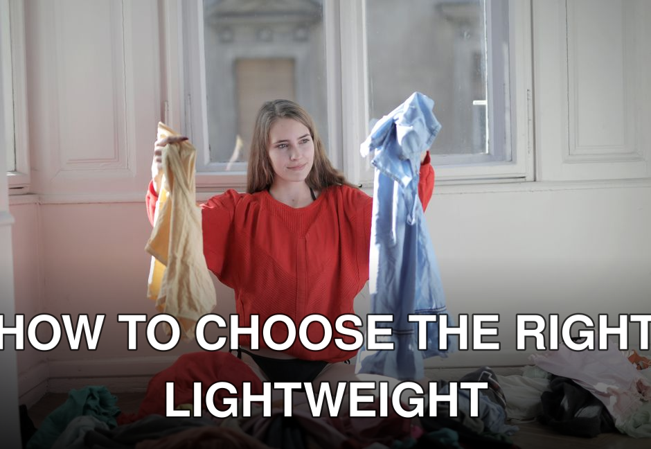 A woman in a red sweater deciding between clothes in a messy room.