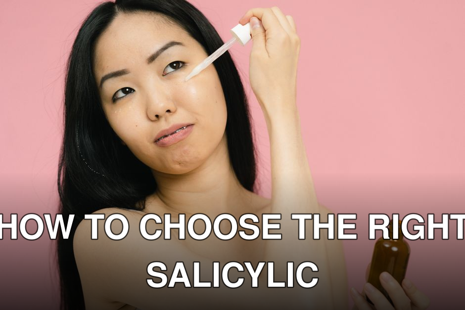 Asian woman applying skincare serum, holding a bottle against a pink backdrop indoors.