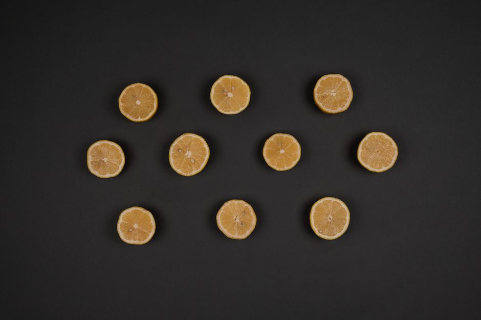 Top view of ripe aromatic lemon circles with juicy flesh and seeds on dark background