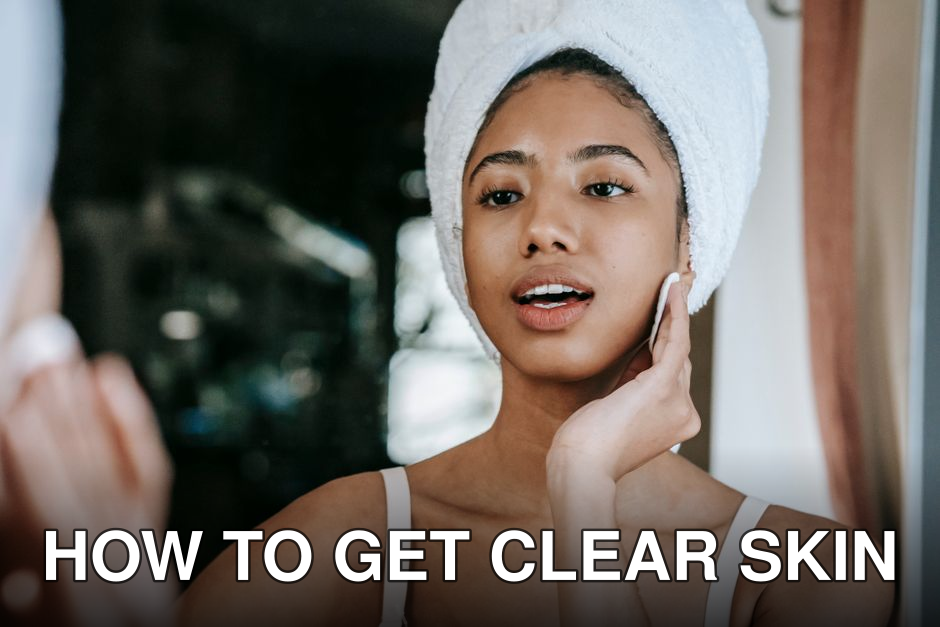 Ethnic female with mouth opened cleaning face with cotton pad while looking at mirror during daily beauty care