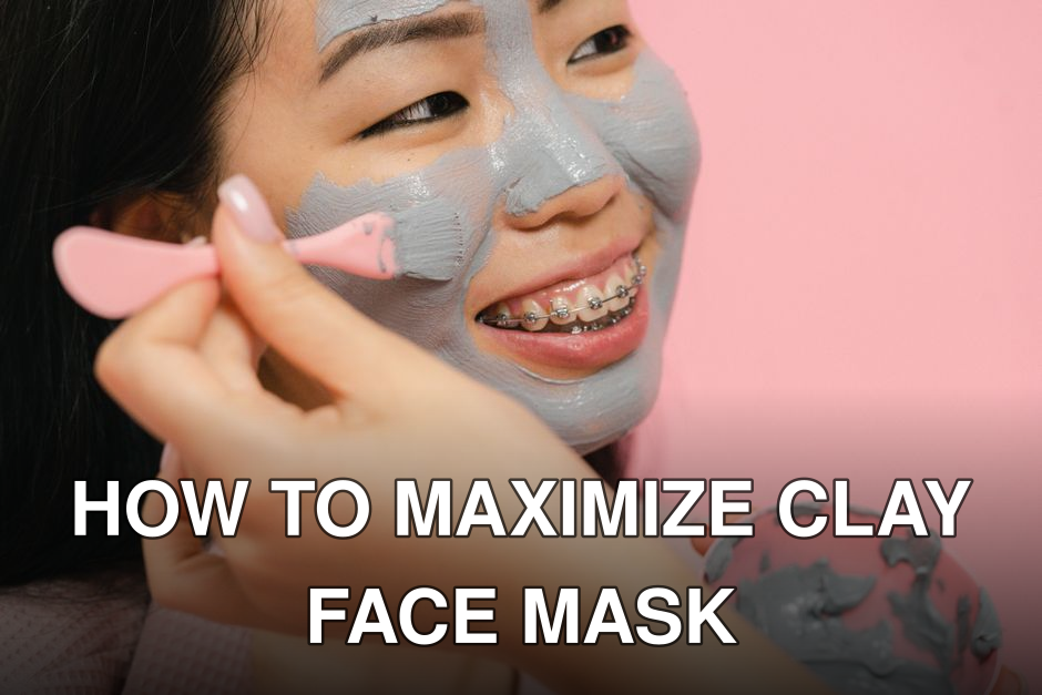 Close-up of a woman with braces applying a clay face mask, smiling cheerfully against a pink background.