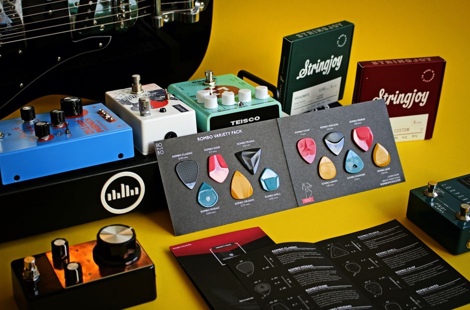 A collection of guitar accessories including pedals and picks displayed on a yellow background.