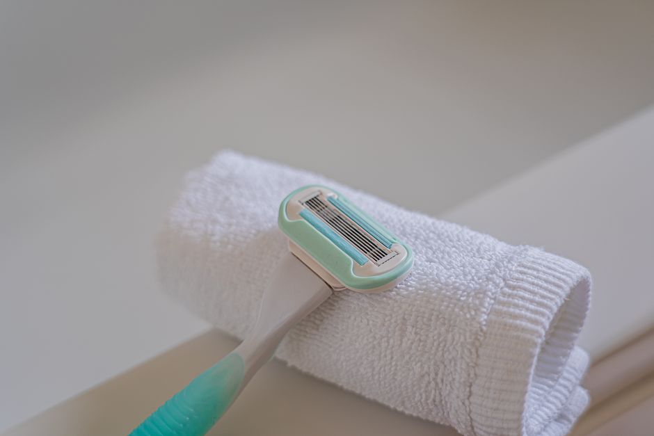 A disposable razor placed on a rolled white towel in a bathroom, highlighting grooming essentials.