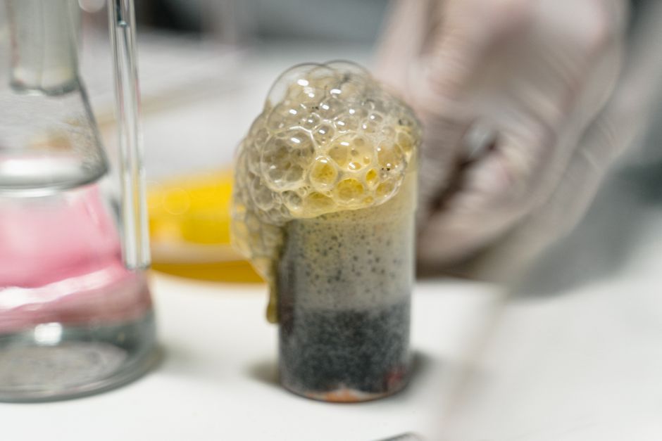 Close-up of a bubbling chemical reaction in a lab setting, showcasing frothy bubbles.