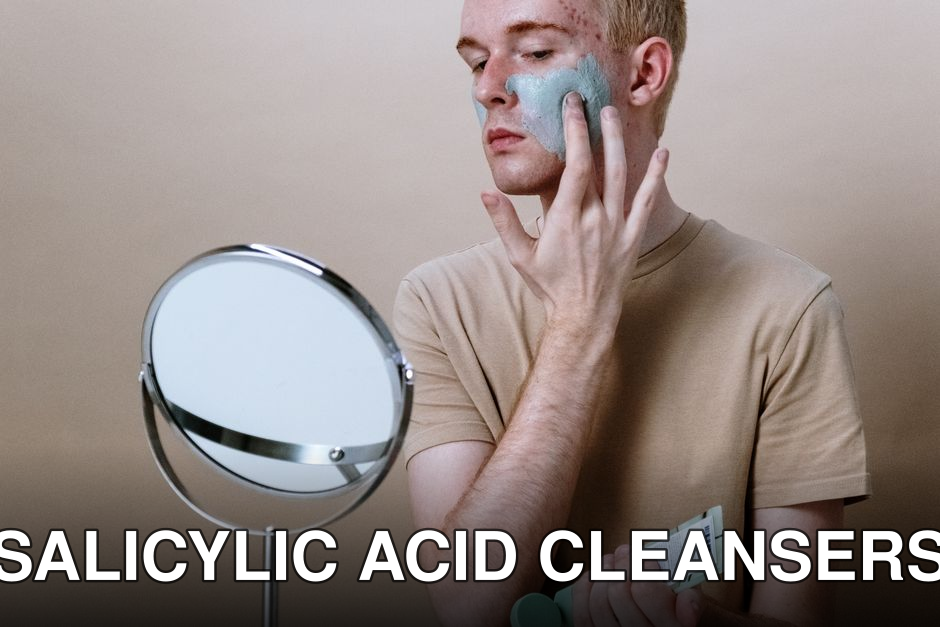 Young man applying clay mask for skincare routine indoors with a mirror.
