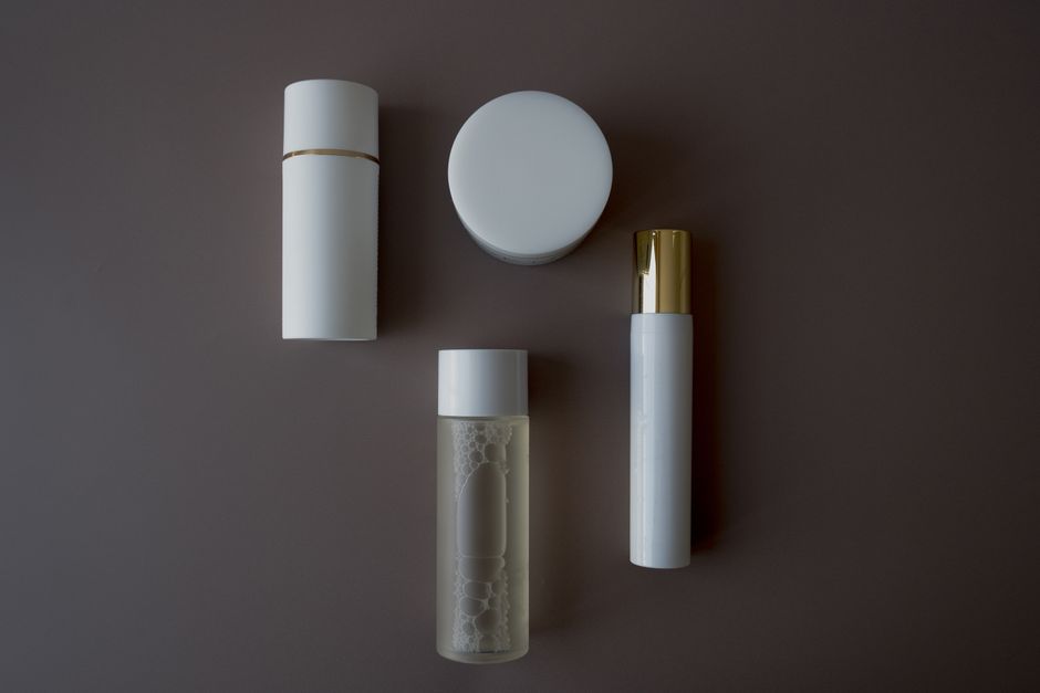 Top view of various skincare bottles and flasks on a sleek gray background.