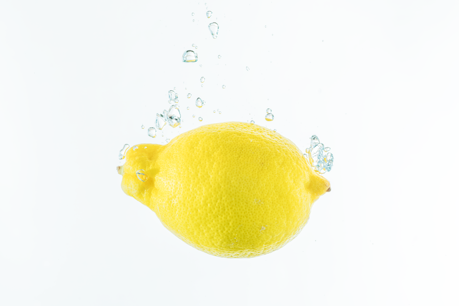 A fresh lemon submerged in water with bubbles, highlighting its refreshing and vibrant nature.