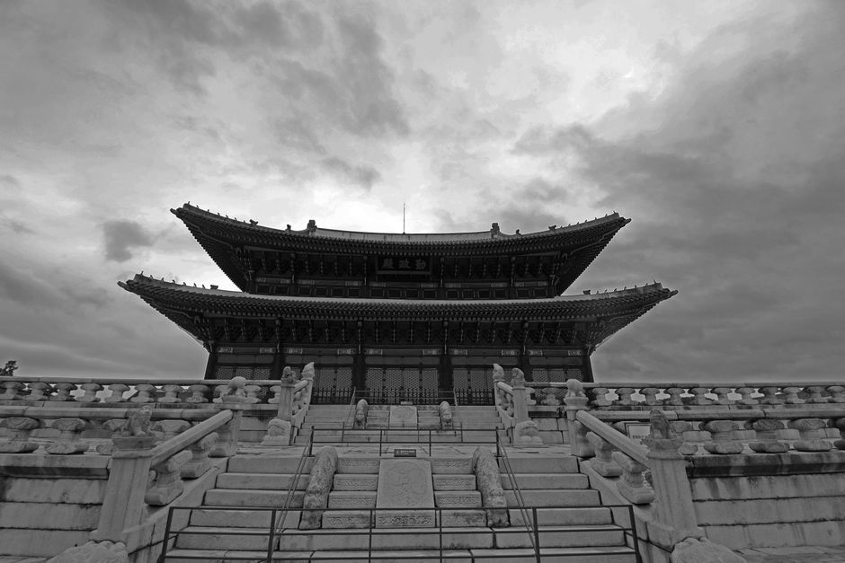 Black and white view of Gyeongbokgung Palace with dramatic clouds. Historic Seoul architecture.