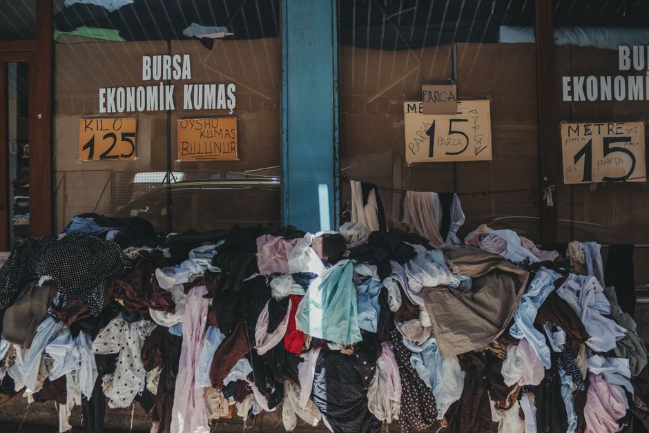 A textile shop in Bursa with a colorful pile of fabrics displayed outside, offering economic prices.