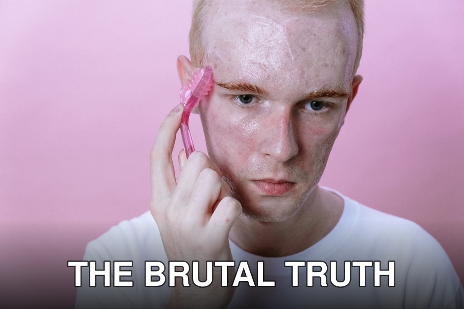 Young man using a pink facial roller on his face against a pink background.