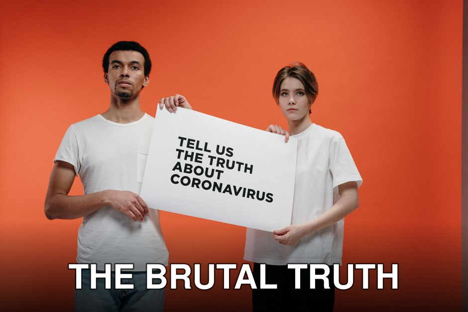 Two people holding a 'Tell Us The Truth About Coronavirus' sign against a vibrant orange background.