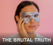 Emotionless young Asian male in white shirt with cosmetic eye mask touching face and looking at camera against pink background