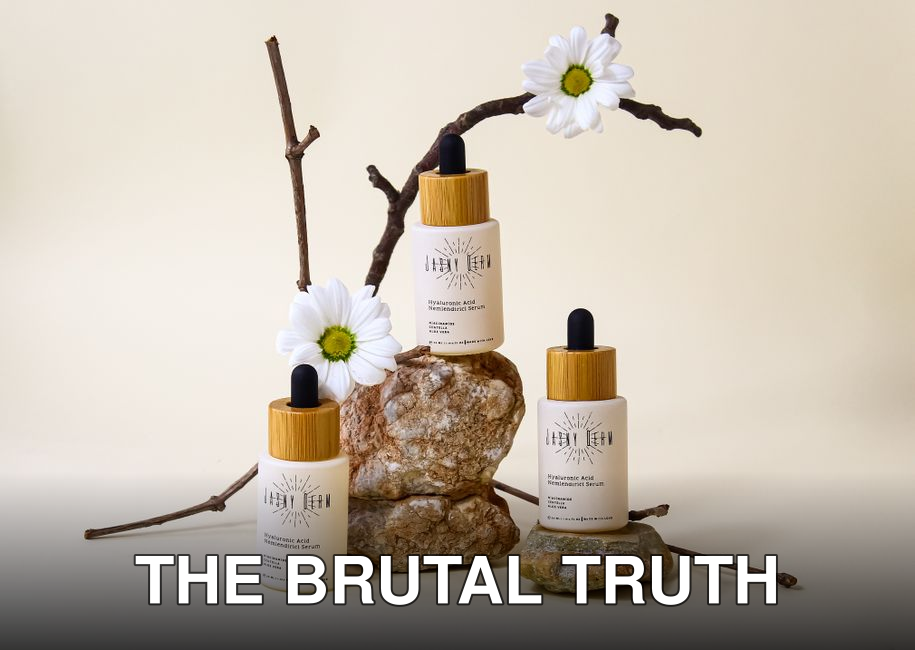 Organic hyaluronic acid serum bottles with floral and stone arrangement on neutral background.