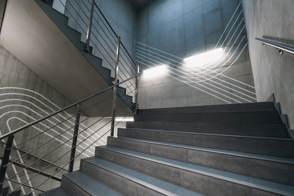 Abstract view of a modern concrete staircase featuring metal railings and geometric patterns.