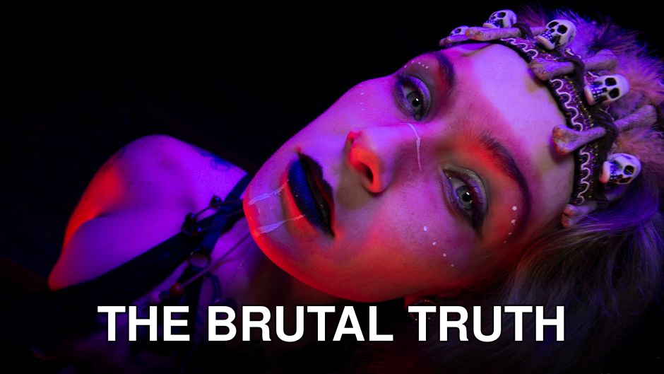 Artistic portrait of a woman with eerie makeup and skull accessories in vivid lighting.