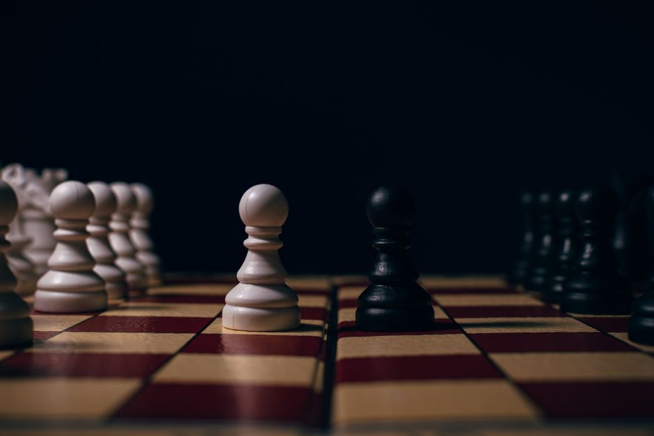 Close-up of chess pawns on a board in a strategic setup, capturing the essence of competition.