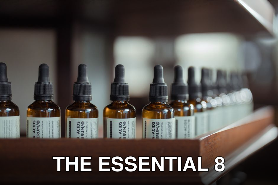 Row of brown serum bottles with dropper caps aligned on a wooden shelf.