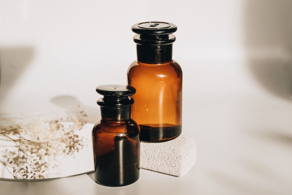 Aesthetic arrangement of amber glass bottles and dried flowers on a minimalist surface.