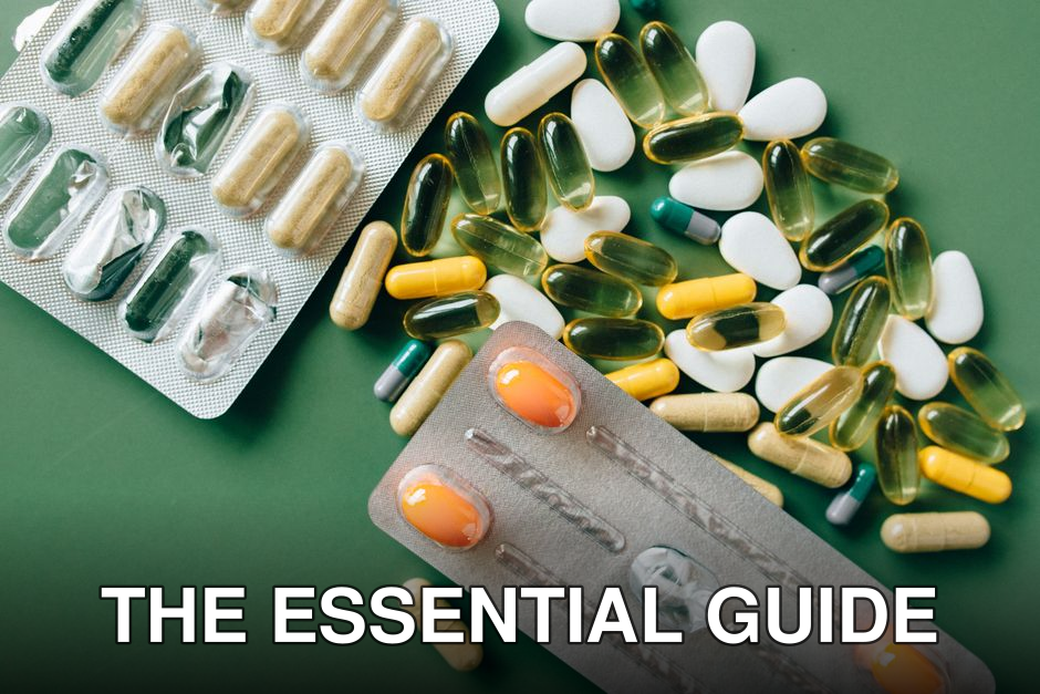 Variety of capsules and tablets laid out on a green surface for healthcare concept.