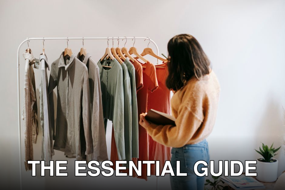 Side view of unrecognizable lady in casual clothes with notebook standing near wardrobe with various multicolored garments on hangers in light shop