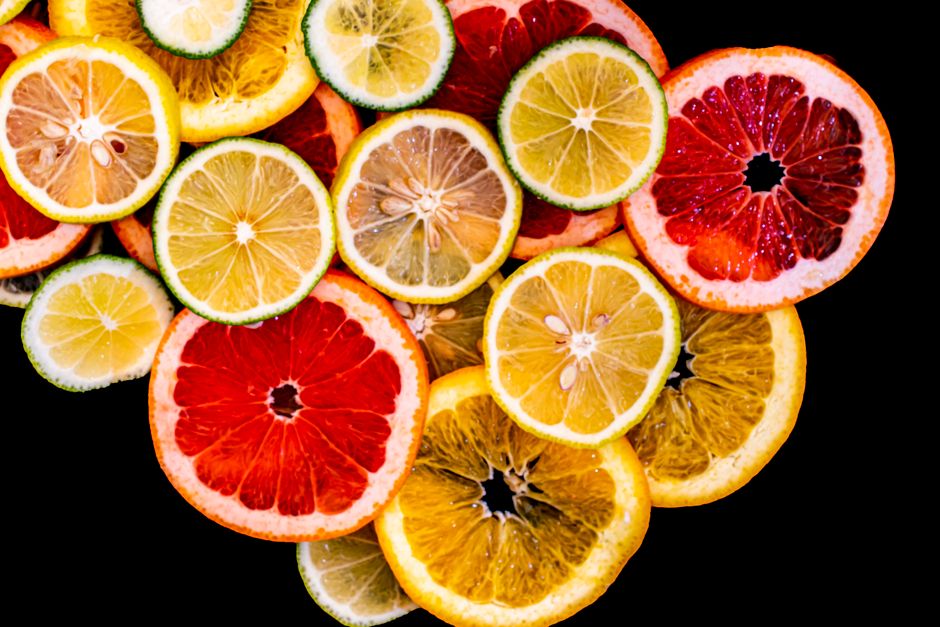 Colorful citrus fruit slices arranged against a black background, showcasing variety and freshness.