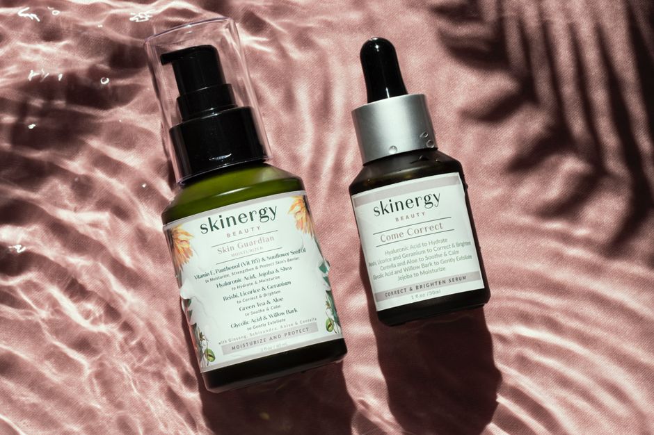 Close-up of luxury skincare bottles on a satin surface with water reflections.
