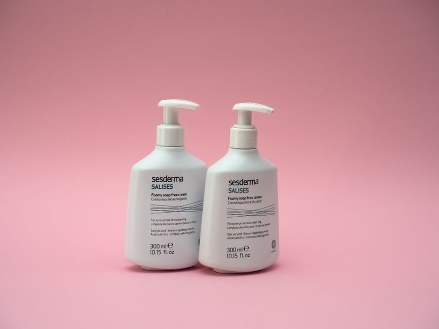 Two bottles of Sesderma Salises foaming cream against a pink backdrop.