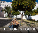 Couple sitting on steps with a map, surrounded by vibrant orange trees in a sunny urban setting.