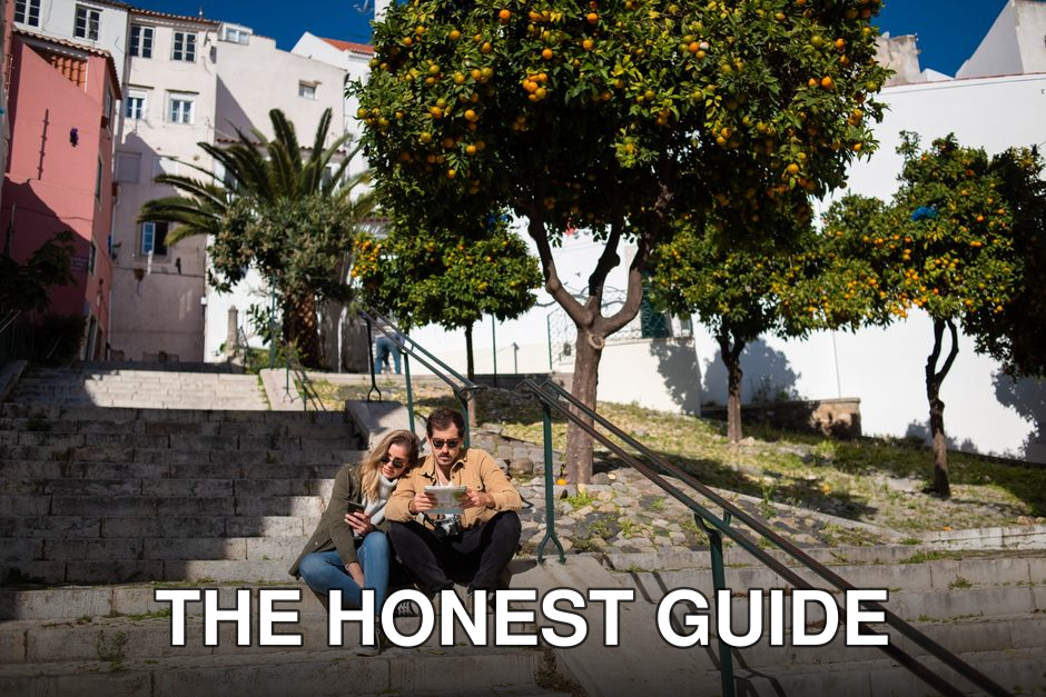 Couple sitting on steps with a map, surrounded by vibrant orange trees in a sunny urban setting.