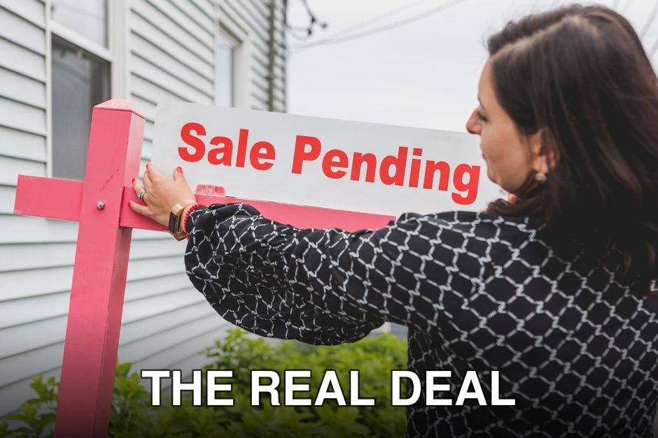 Female realtor adjusts sale pending sign on a property, indicating an upcoming sale closure.