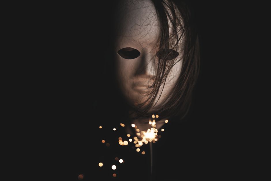 A mysterious and eerie scene of a mask with a sparkler, set against a dark background, creating a haunting ambiance.