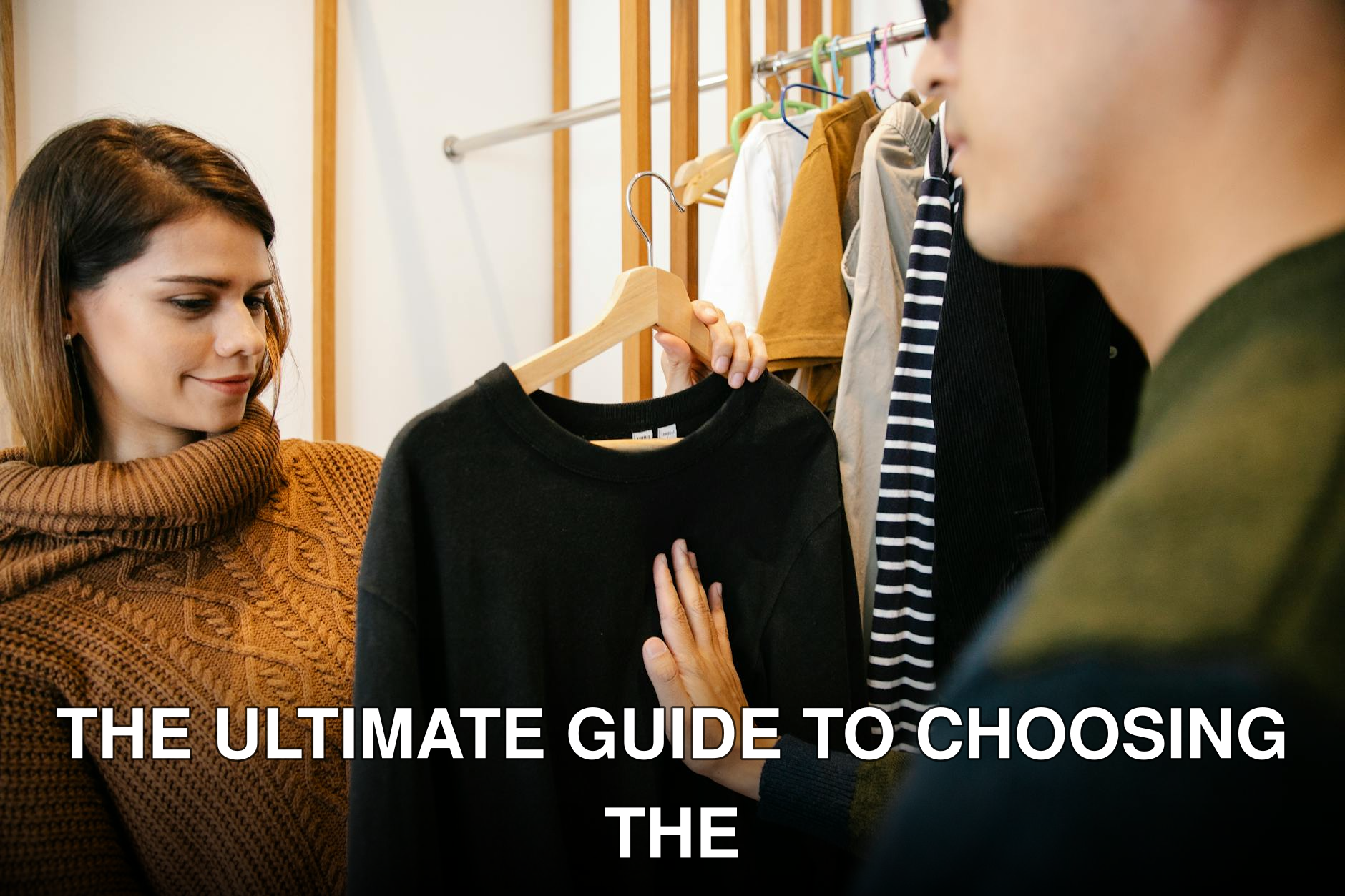 A visually impaired man with a female assistant selecting a sweater indoors.