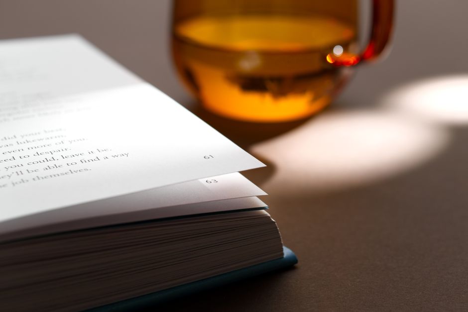 Artistic photo of open book pages under sunlight with a translucent glass in frame.